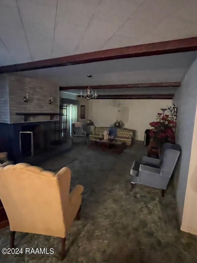 105 S 1st St, Gueydan, LA 70542 - carpeted living room featuring beam ceiling and an inviting chandelier