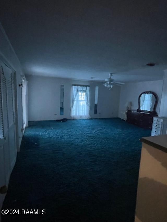 105 S 1st St, Gueydan, LA 70542 - unfurnished living room with carpet and a ceiling fan