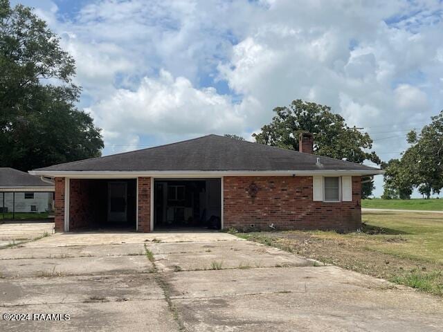105 S 1st St, Gueydan, LA 70542 - view of front of home featuring an attached garage, driveway, brick siding, and a chimney