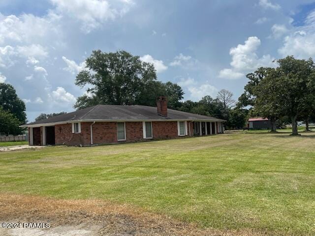 105 S 1st St, Gueydan, LA 70542 - rear view of property featuring a chimney, an attached garage, brick siding, and a lawn