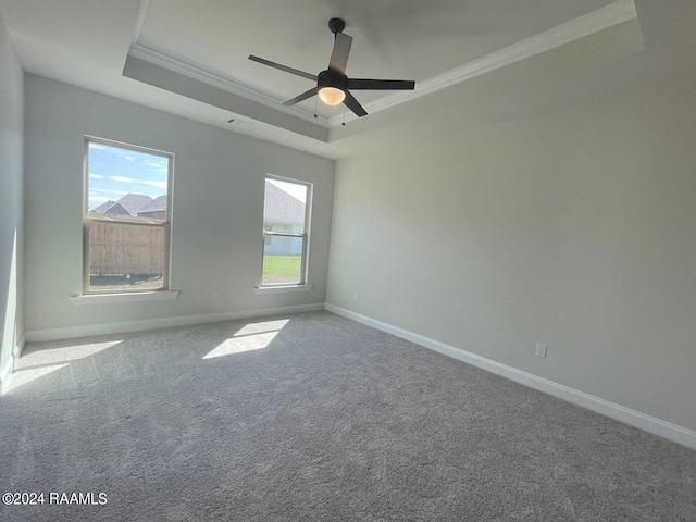 carpeted empty room with a raised ceiling, ceiling fan, and crown molding