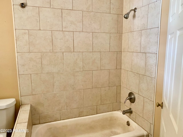 bathroom with toilet and tiled shower / bath