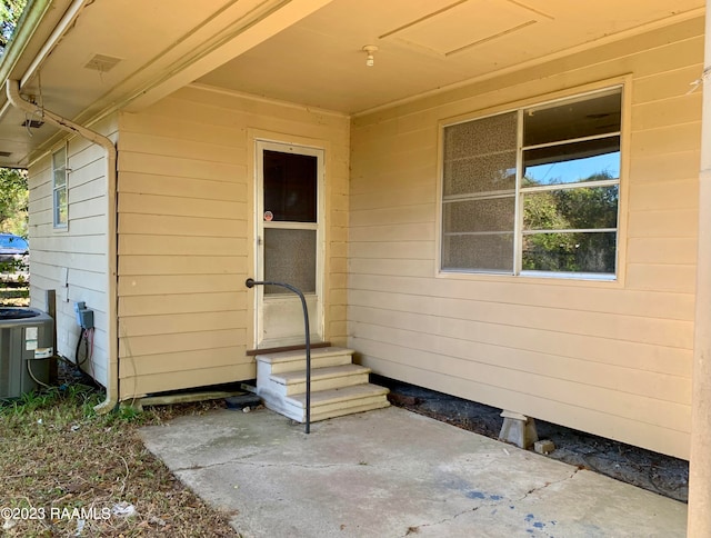 view of exterior entry with central AC and a patio area