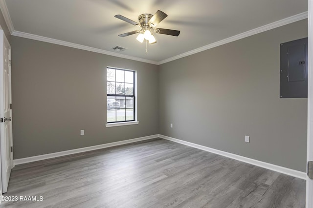 spare room with electric panel, visible vents, wood finished floors, and crown molding