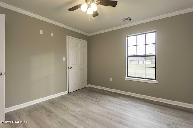 spare room featuring visible vents, crown molding, ceiling fan, baseboards, and wood finished floors