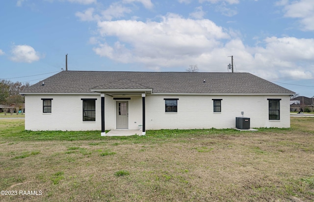 rear view of house with a yard, cooling unit, and a shingled roof