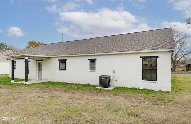 back of house with cooling unit and a yard