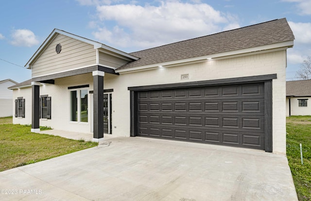 view of front of property featuring driveway, roof with shingles, a front lawn, a garage, and brick siding