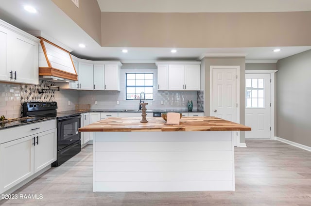 kitchen with a kitchen island, light wood-type flooring, tasteful backsplash, and black range with electric cooktop