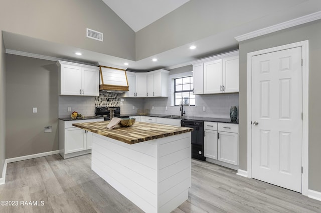 kitchen with visible vents, butcher block counters, custom range hood, black appliances, and a sink