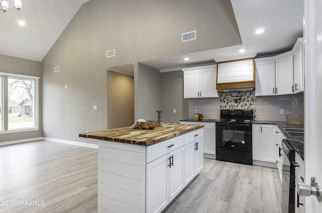 kitchen with visible vents, premium range hood, light wood-style flooring, butcher block countertops, and black electric range