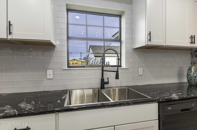 kitchen with white cabinetry, dishwashing machine, tasteful backsplash, dark stone counters, and sink