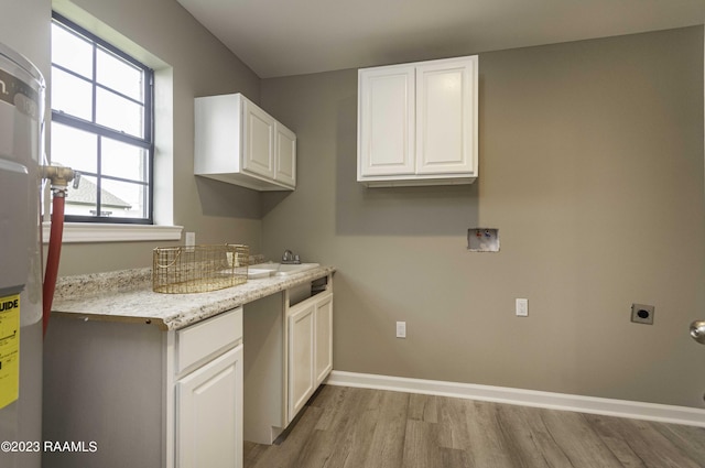 clothes washing area with hookup for a washing machine, baseboards, cabinet space, electric dryer hookup, and light wood-type flooring