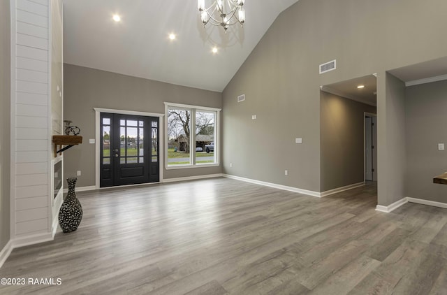 unfurnished living room with baseboards, wood finished floors, visible vents, and a chandelier