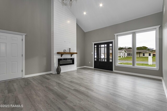 entryway featuring high vaulted ceiling, a fireplace, and light hardwood / wood-style flooring