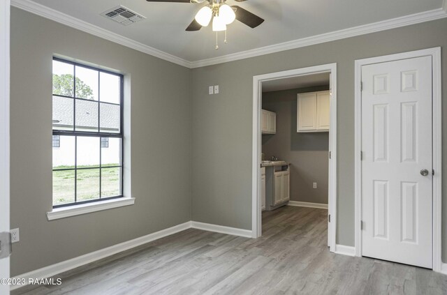 empty room featuring plenty of natural light, ceiling fan, crown molding, and light hardwood / wood-style flooring