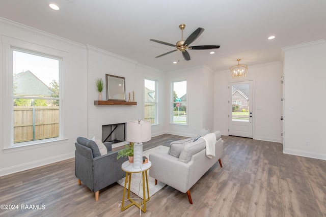 living room with ornamental molding, dark wood-type flooring, and ceiling fan with notable chandelier