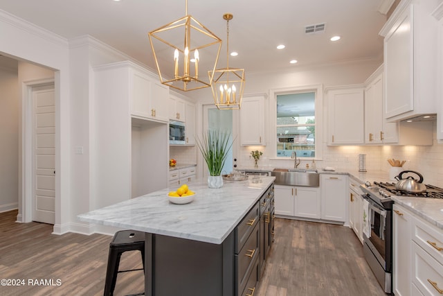 kitchen featuring stainless steel gas range oven, pendant lighting, a center island, white cabinets, and sink