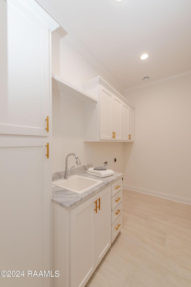 laundry area with ornamental molding, cabinets, hookup for an electric dryer, and sink