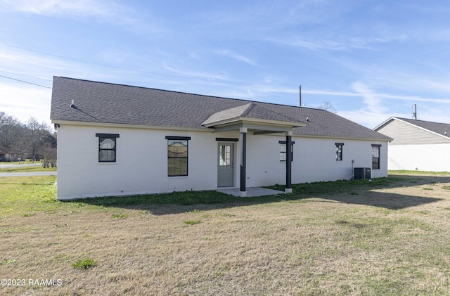 back of property with central air condition unit and a lawn