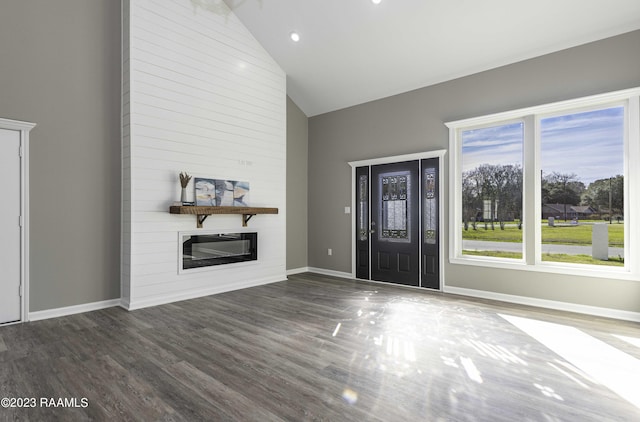 unfurnished living room featuring a wealth of natural light, a large fireplace, dark wood-type flooring, and high vaulted ceiling