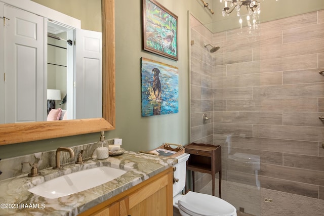 bathroom with a tile shower, an inviting chandelier, vanity, and toilet