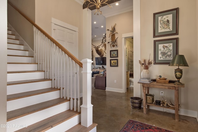 entrance foyer with ornamental molding and a chandelier