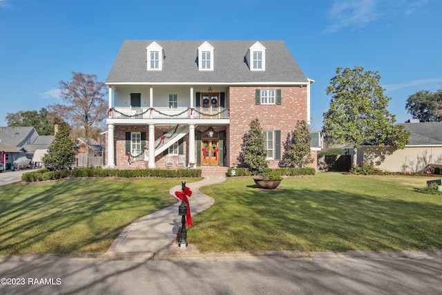 view of front of house with covered porch, a balcony, and a front lawn