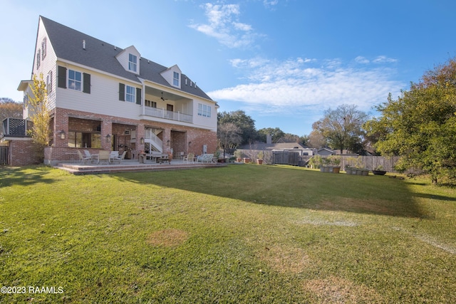 back of property with a lawn, ceiling fan, a balcony, and a patio