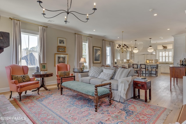 living room with light hardwood / wood-style floors, an inviting chandelier, and crown molding