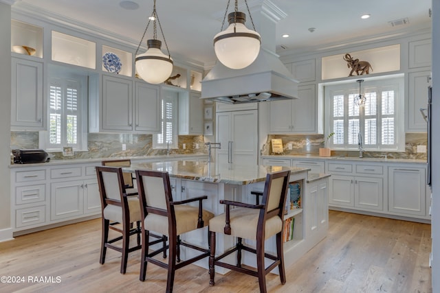 kitchen featuring decorative light fixtures, a center island, white cabinetry, and ornamental molding