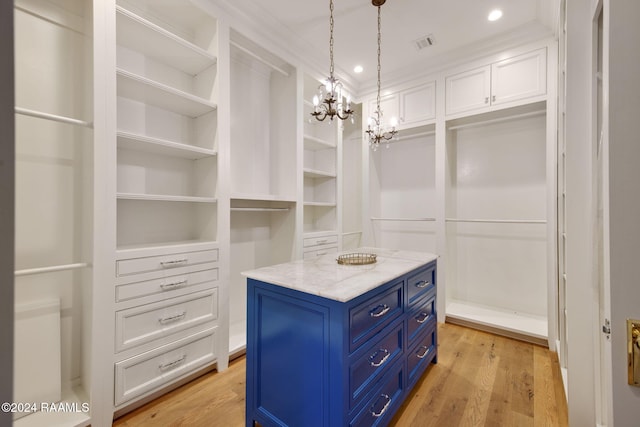 walk in closet featuring a chandelier and light hardwood / wood-style flooring