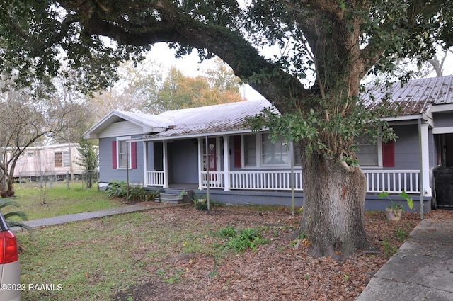 single story home featuring covered porch, fence, and metal roof