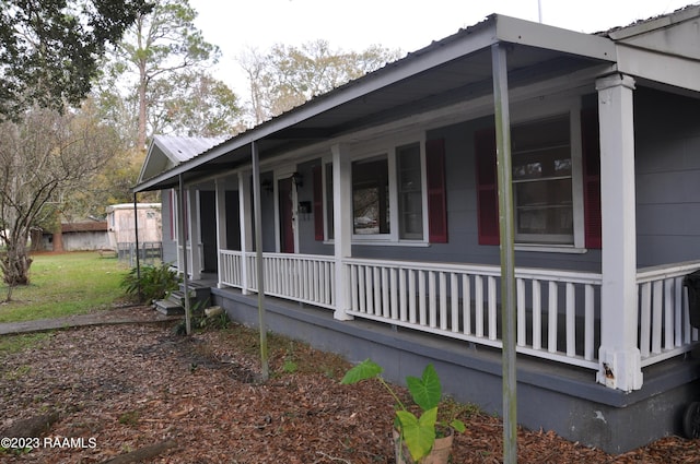 view of side of home featuring metal roof and a porch