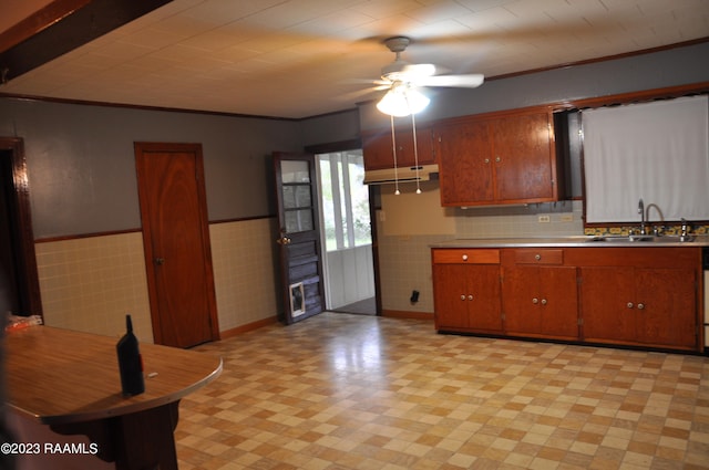 kitchen featuring ceiling fan, tile walls, ornamental molding, and sink