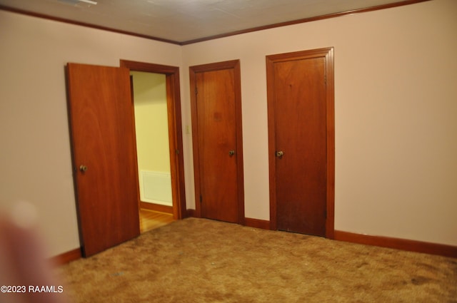 unfurnished bedroom featuring baseboards, two closets, carpet floors, and ornamental molding