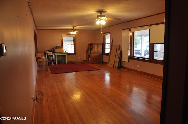 unfurnished living room featuring a wealth of natural light, wood finished floors, ceiling fan, and baseboards