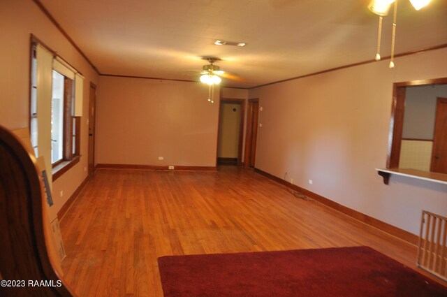 empty room with wood-type flooring, ceiling fan, and crown molding