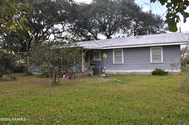 ranch-style house with central AC unit, metal roof, and a front lawn