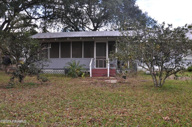 view of front facade featuring a sunroom and a front lawn