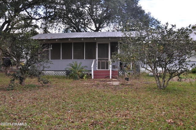 view of front facade featuring a front yard, a sunroom, and metal roof
