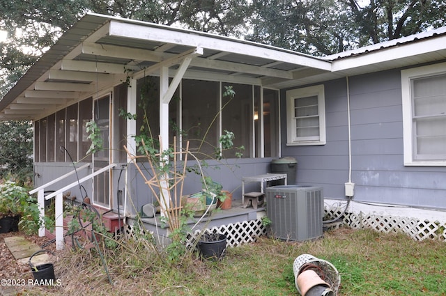 view of side of home with metal roof, cooling unit, and a sunroom