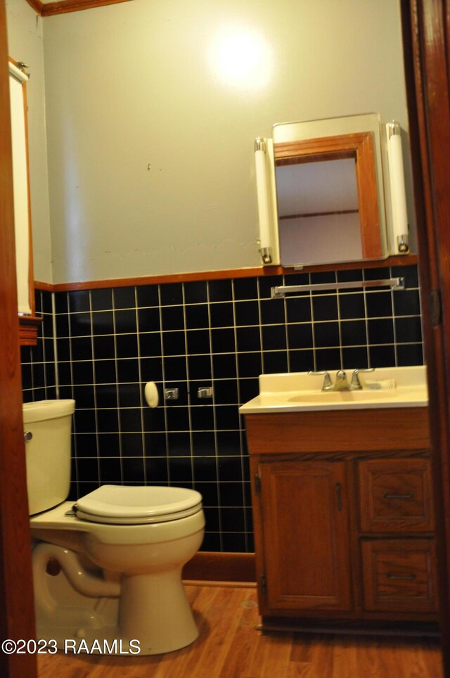 bathroom with hardwood / wood-style flooring, vanity, toilet, and tile walls