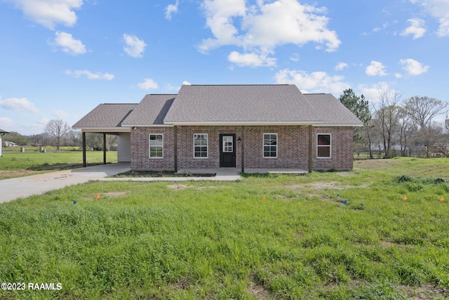 view of front of property featuring a carport, brick siding, a front lawn, and driveway