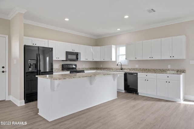 kitchen featuring a center island, visible vents, white cabinetry, black appliances, and a kitchen breakfast bar