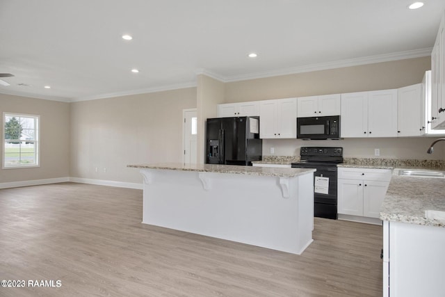 kitchen featuring a sink, white cabinetry, a center island, black appliances, and crown molding