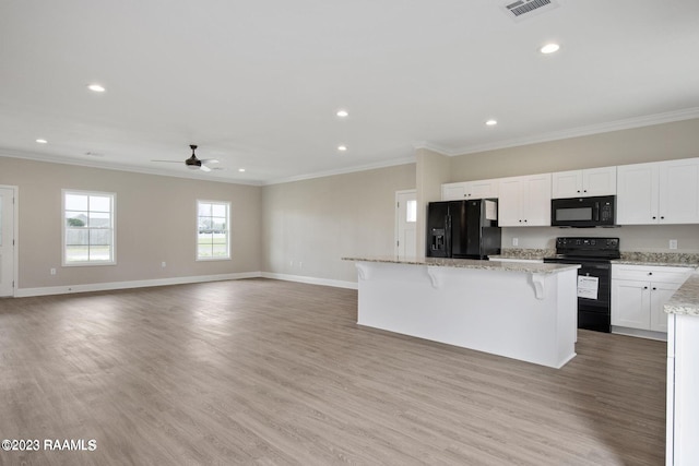 kitchen with a kitchen island, visible vents, light wood-type flooring, black appliances, and crown molding