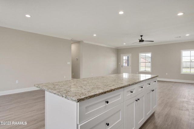 kitchen featuring ornamental molding, a kitchen island, light wood finished floors, and baseboards