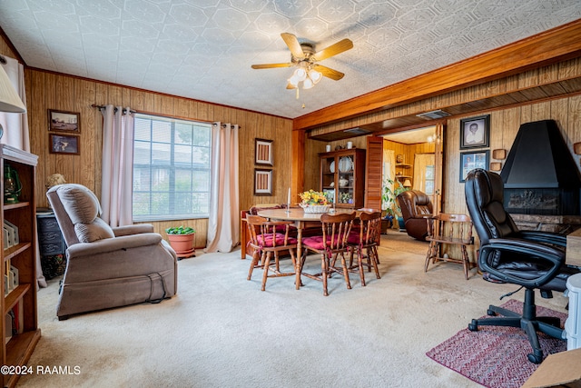 dining room with wood walls, ceiling fan, light carpet, and ornamental molding