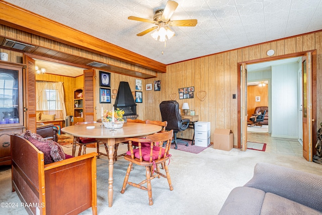 dining room featuring crown molding, ceiling fan, light carpet, and wooden walls